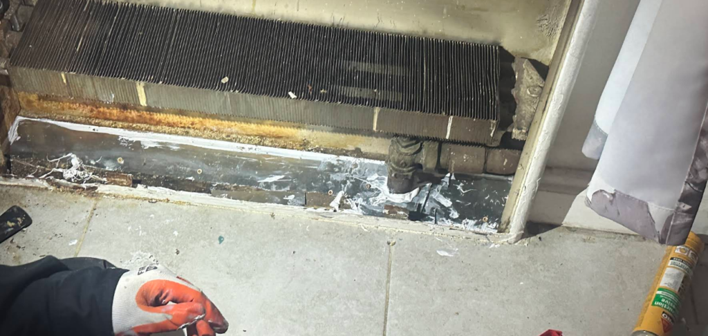 Floor gap by a radiator sealed with metal and elastomeric sealant, NYC