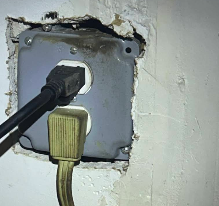 Rodent grease and rub marks around a wall outlet before sealing, Manhattan
