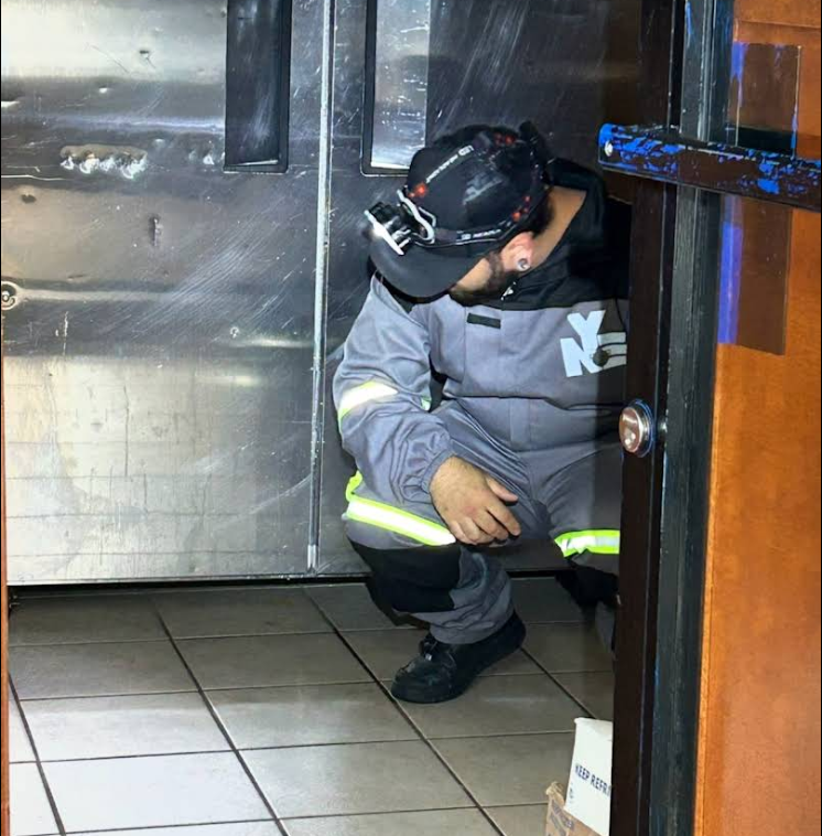 Inspecting under commercial kitchen equipment at a Brooklyn bakery