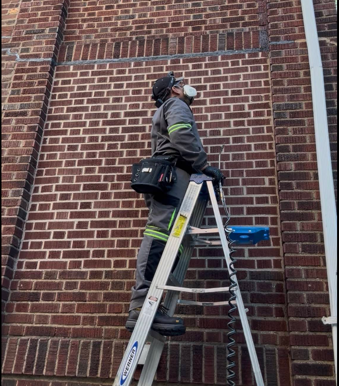 NYE technician treating a wasp/hornet nest on a ladder, NYC