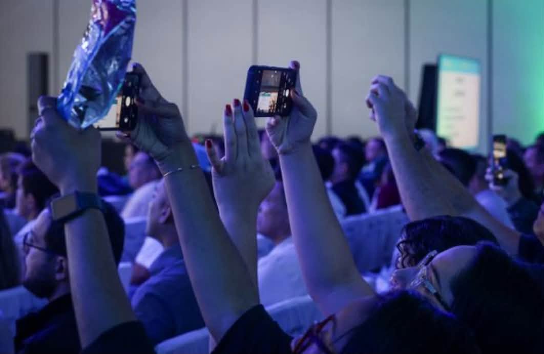 Attendees at ExpoPrag 2026 photographing the Trio Protocol slides during the German cockroach lecture