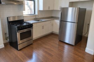 NYC rental kitchen with the stove and refrigerator pulled out for a German cockroach treatment
