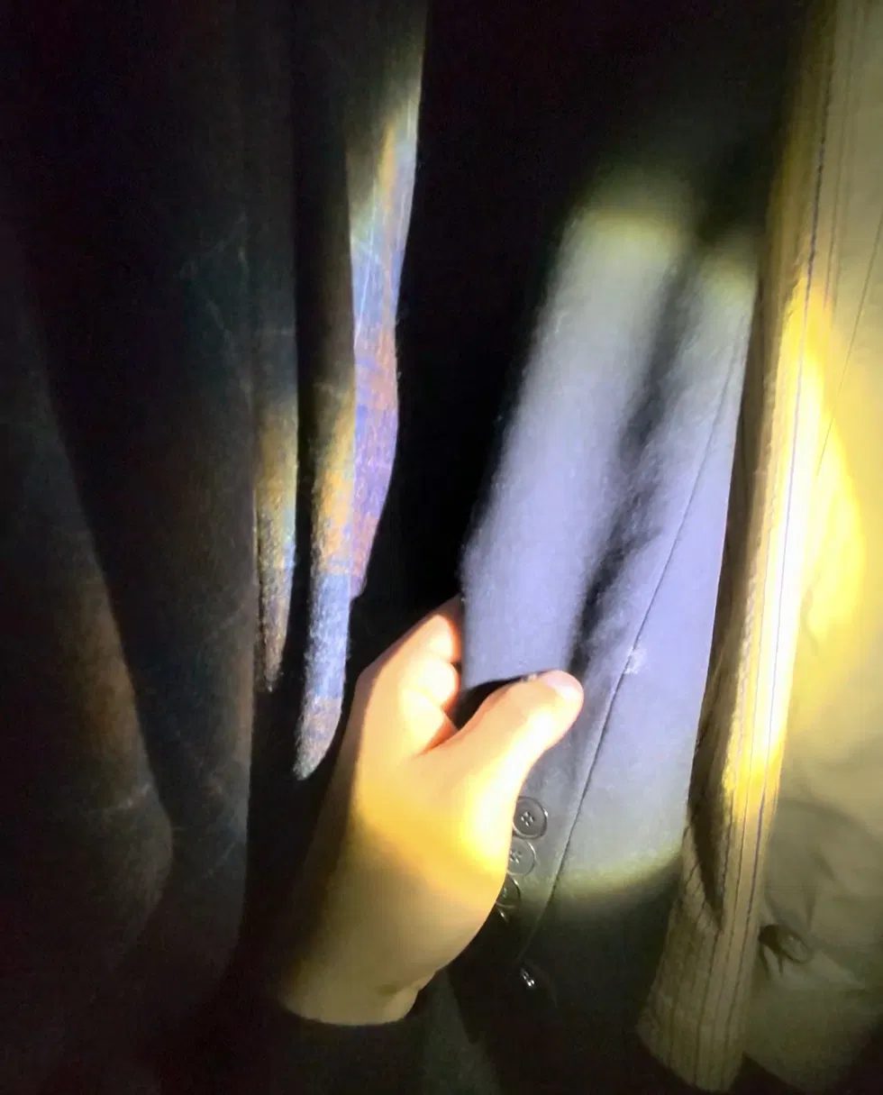 Technician inspecting a wool garment in a closet under a work light
